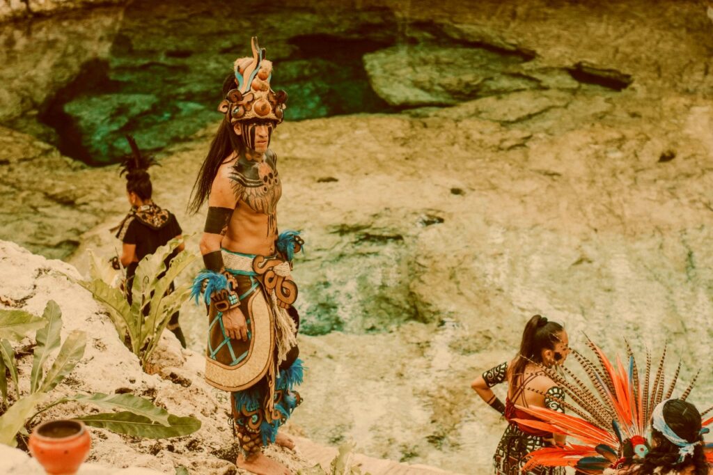 Representación de sabiduría ancestral y símbolos rituales junto a un entorno natural, como metáfora del autoconocimiento y los mapas simbólicos del ser humano.